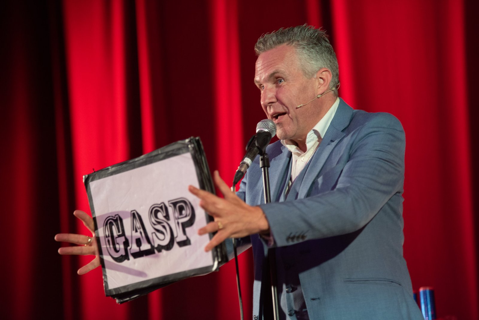 Male magician holds up a sign which says gasp