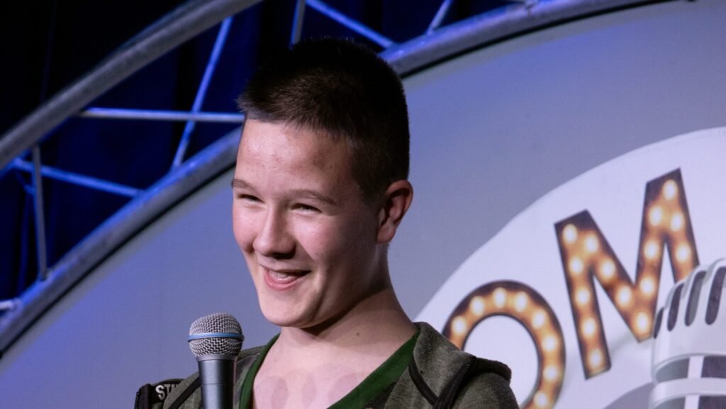 Young boy holding microphone and telling jokes