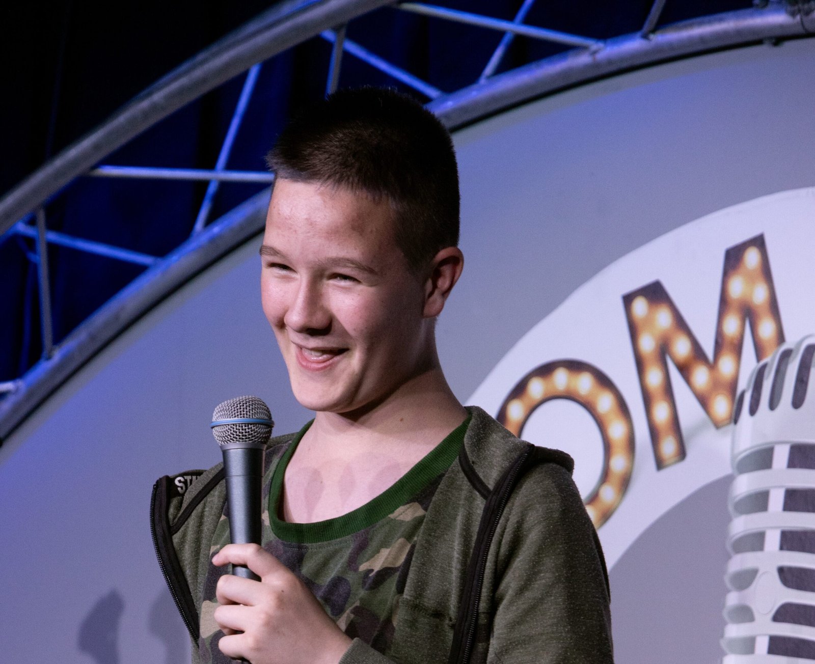 Young boy holding microphone and telling jokes