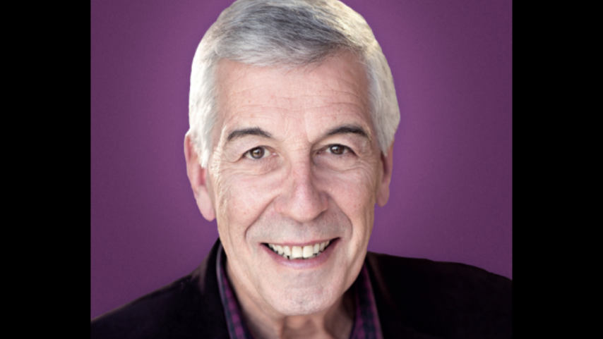 Jeffrey Holland smiling on a purple background